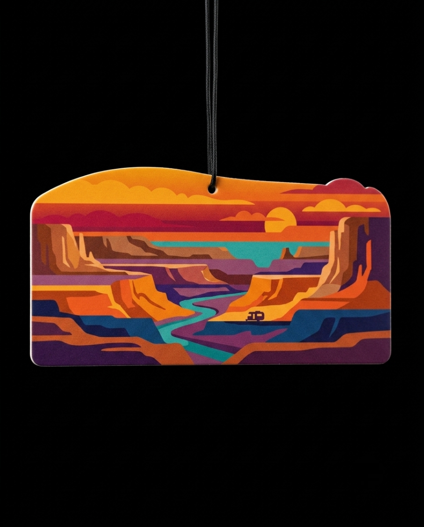 A rectangular car air freshener ornament with rounded corners, featuring a colorful graphic illustration of a canyon landscape at sunset, suspended by a black string against a solid black background.