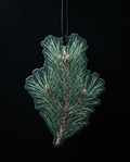 A pine needle-shaped air freshener or car fragrance ornament hanging from a black cord against a solid black background.
