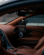Car interior with a 'The Ember' air freshener hanging from the rearview mirror.