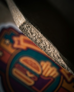 Close-up of a textured gray fabric or foam strip layered over a colorful blurred graphic background featuring a burger and fries illustration.