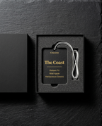 Black packaging with a label and white cable on a dark stone background