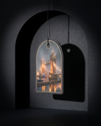 An arched acrylic wall tag featuring a printed nighttime photograph of Tower Bridge in London, suspended by a black cord against a dark gray arched backdrop.