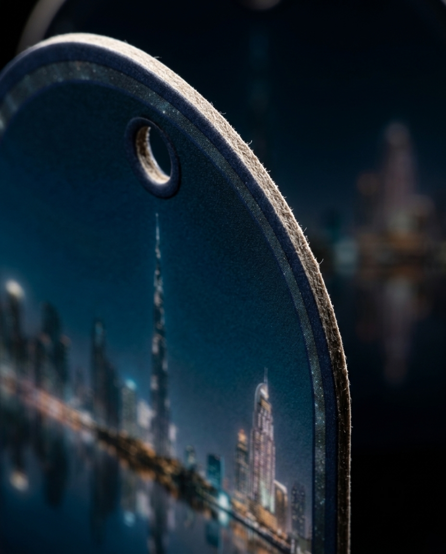 A close-up of a dark, arched accessory with a printed city skyline design and a small circular cutout near the top, shown against a blurred dark background.