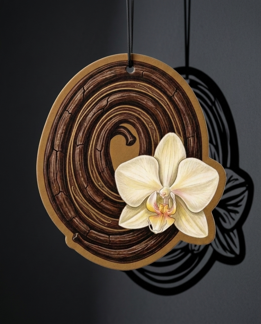 A decorative oval wall hanging or plaque with a dark brown wood-grain spiral design and a cream-colored orchid flower attached near the lower right, shown hanging against a dark gray background.