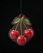 A cherry-shaped hanging ornament or plaque with three glossy red cherries, green leaves, and stems on a dark brown background, suspended by a black cord against a black backdrop.