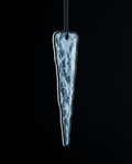 An elongated, tapered glass ornament with a textured, icy blue and white pattern inside a clear glass body, suspended by a black cord against a solid black background.