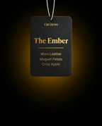 Black air freshener tag with 'The Ember' description on a dark background