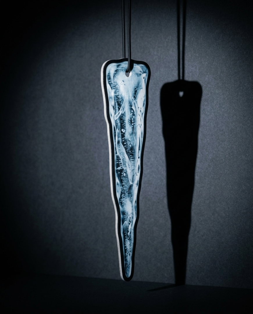 An elongated, icicle-shaped pendant with a swirling white and light blue marbled pattern inside a clear resin or glass-like frame, hanging against a dark gray background with a sharp black shadow cast to the right.